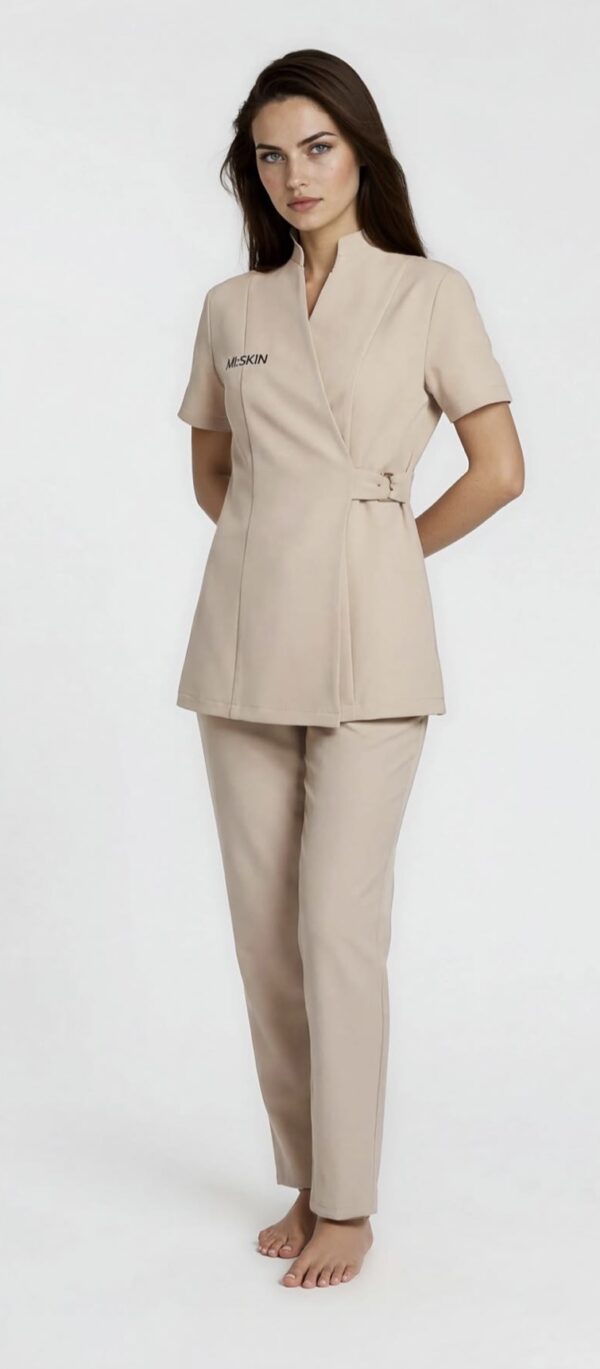 Beige spa uniform set with wrap-style tunic, side buckle detailing, and straight-fit pants