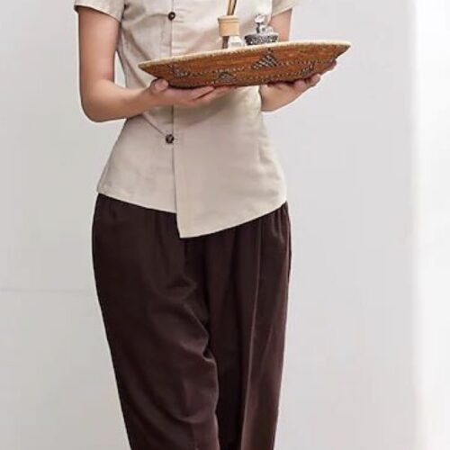 Beige spa uniform with asymmetrical button front, mandarin collar, and brown straight-fit pants