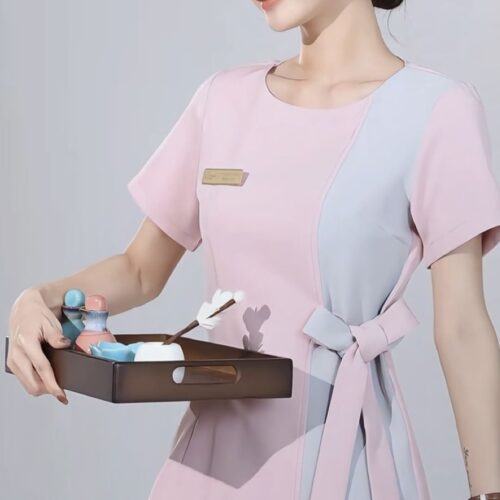 Pink spa uniform with grey side panel, waist tie detailing, and short sleeves