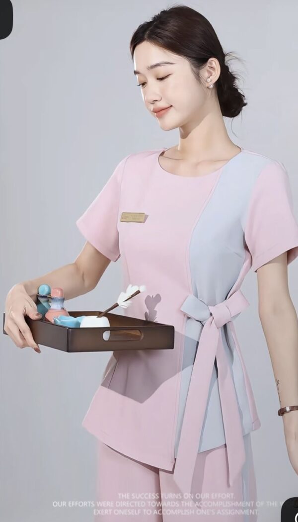 Pink spa uniform with grey side panel, waist tie detailing, and short sleeves